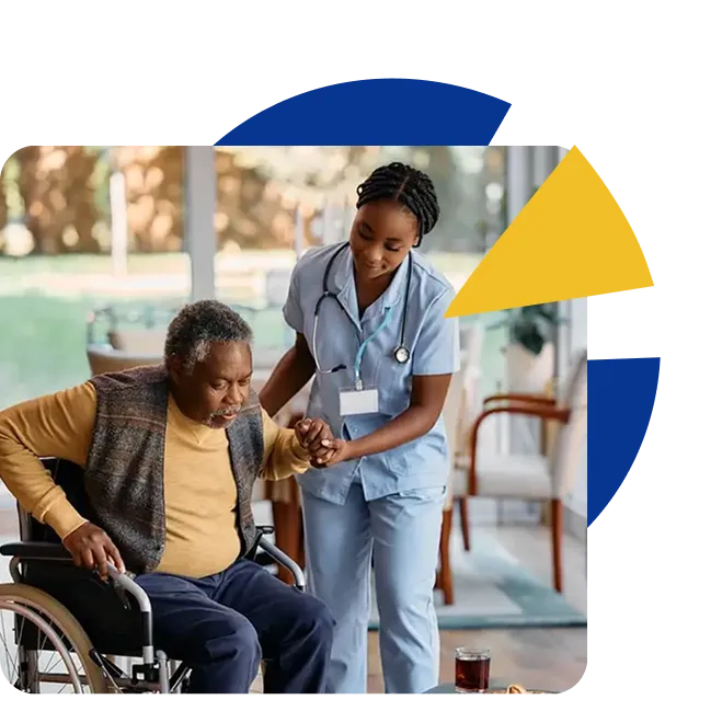 A nurse helps an older resident stand up from his wheelchair in a bright lounge.